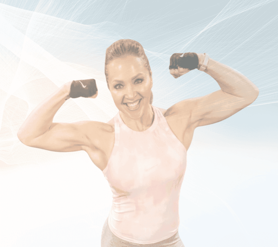 Fit woman smiling, flexing both biceps in a pink tank top and gloves.